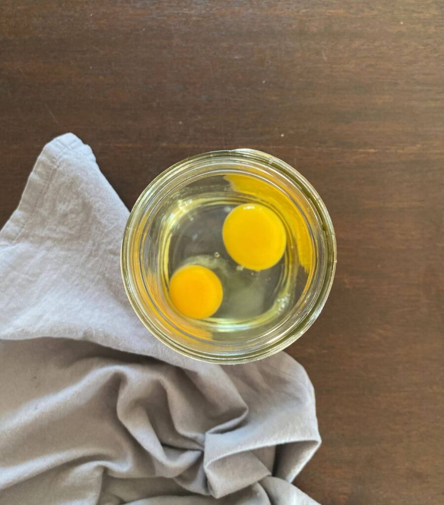 2 raw eggs in a glass jar.