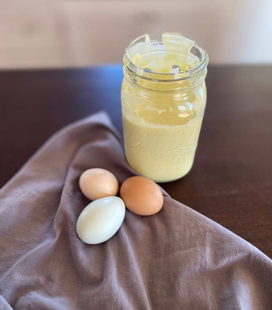 A jar of mayo without the lid and three coloured eggs.