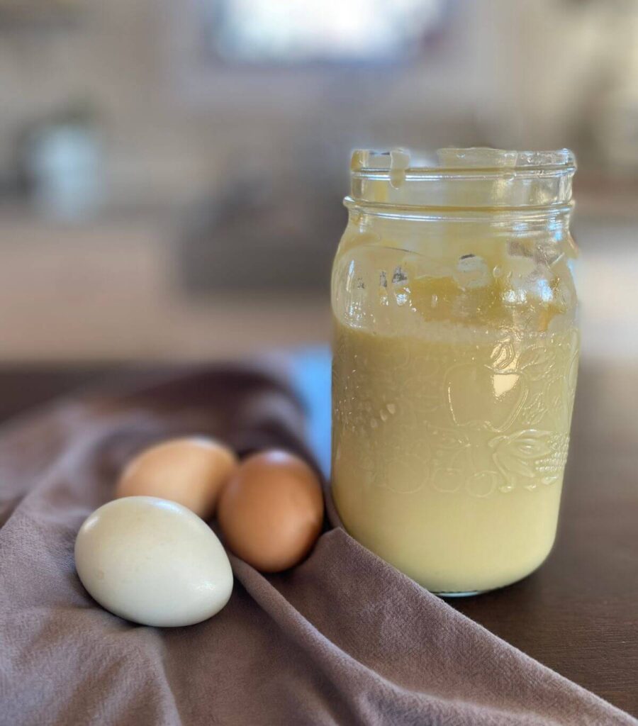 A jar of homemade mayo with 3 colourful eggs.
