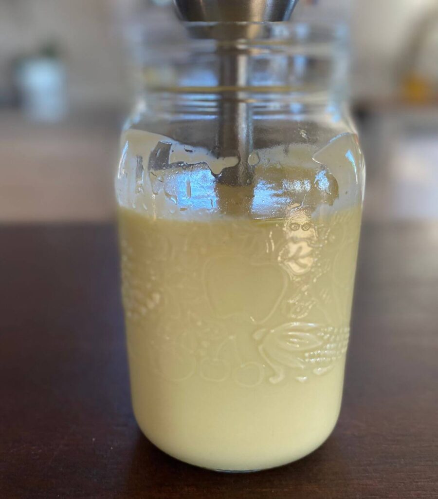 Close up of homemade mayo completely blended with the immersion blender still inside.