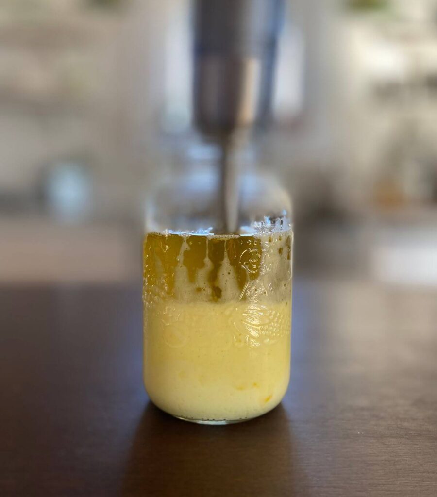 Blending oil and eggs together to make homemade mayo with an immersion blender.