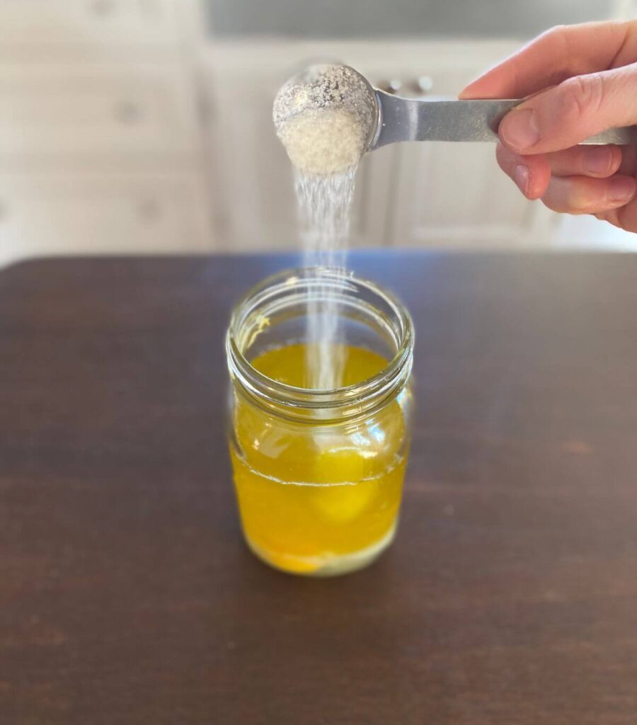 Pouring cane sugar into a jar of eggs and oil.