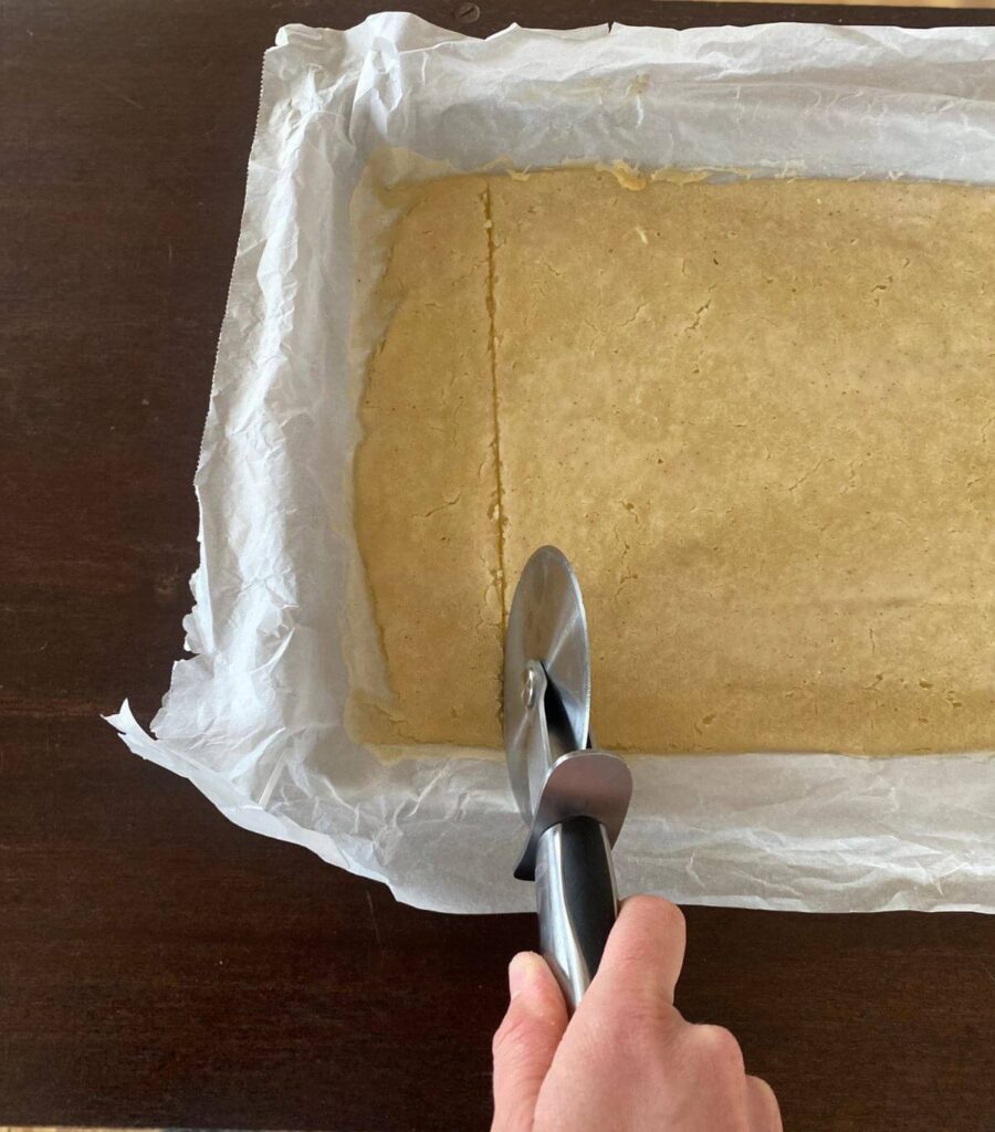 Staring to score the lightly baked cracker batter with a pizza cutter.