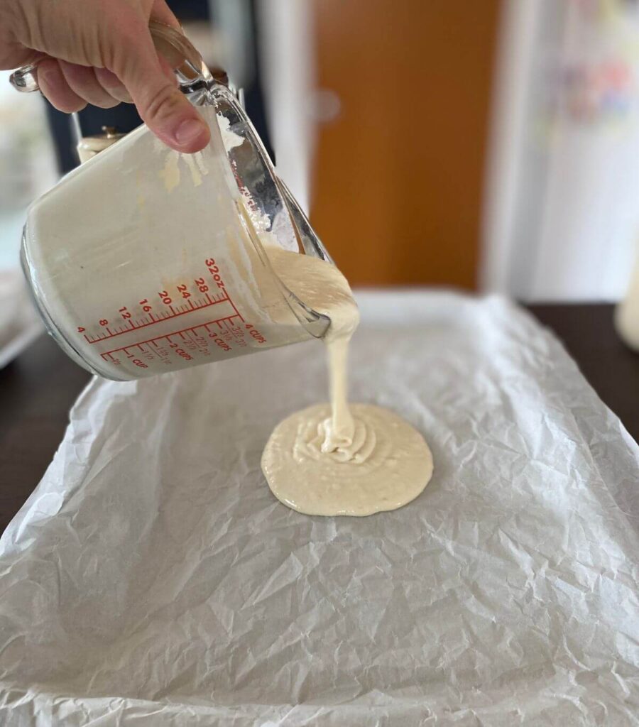 Oozing the sourdough discard cracker mixture out onto the baking sheet parchment paper.