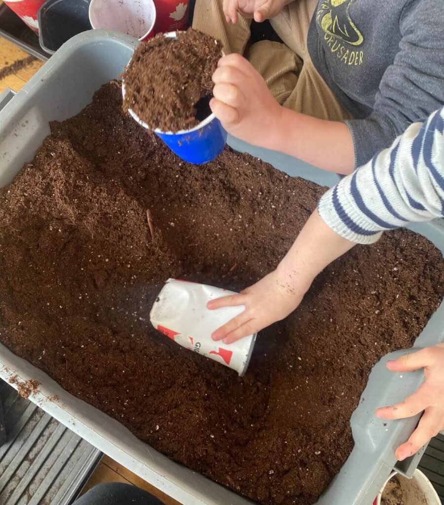 Two children filling flower pots with soil.