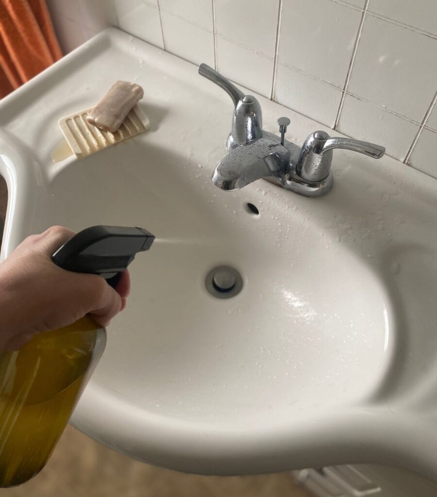 Spraying a sink with homemade cleaner.