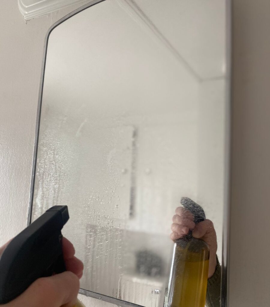 Spraying a mirror with homemade cleaner.