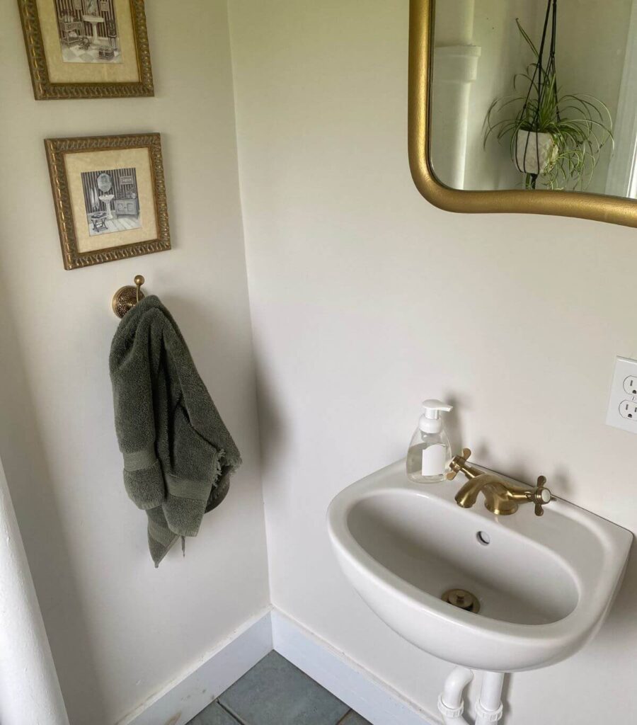 A cute little bathroom with an IKEA sink with golden fixtures and pretty artwork on the wall.
