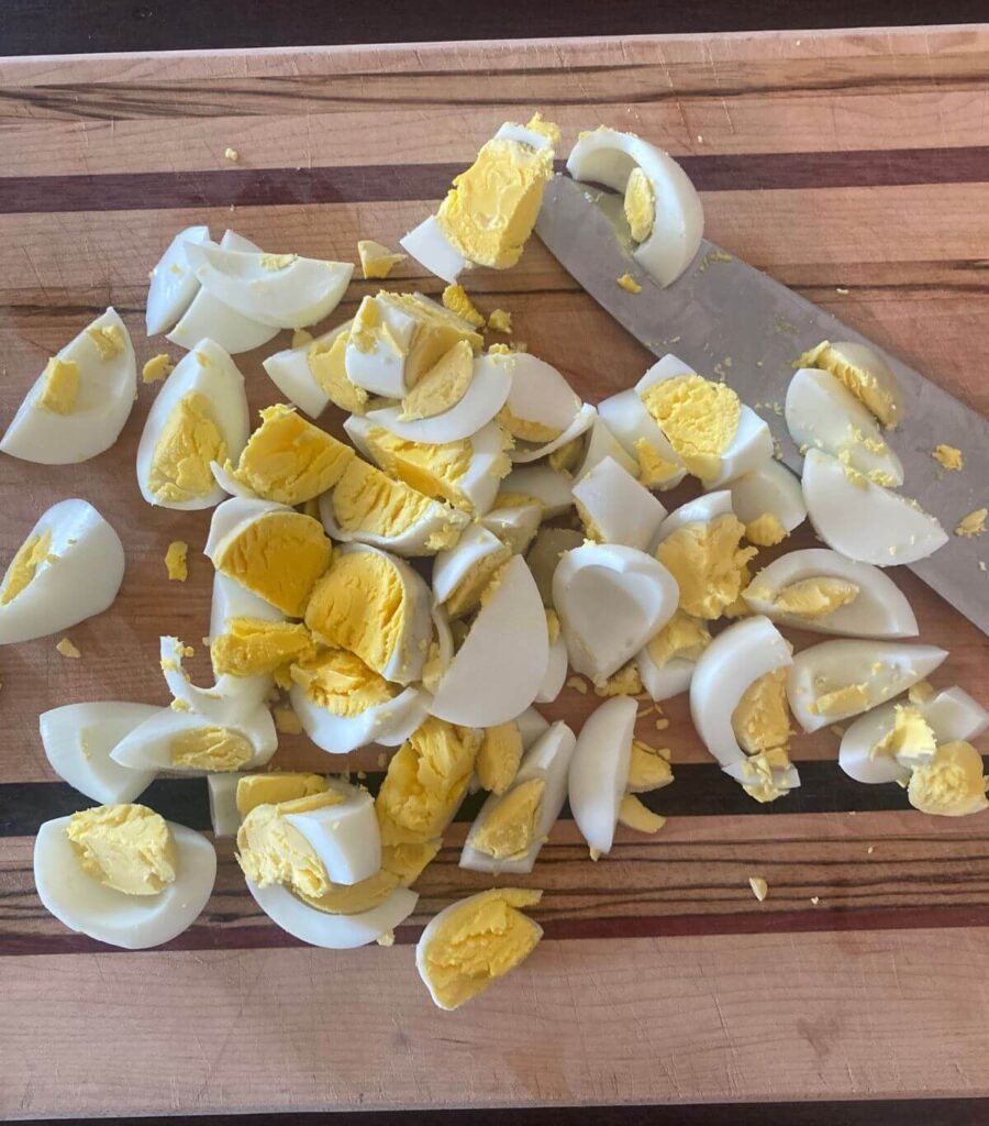 Chopped bright yellow yolked hard-boiled eggs on a wooden cutting board.